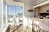 Bright and modern apartment kitchen with sleek cabinetry, chic bar seating, and panoramic city views from expansive windows.