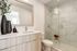Elegant bathroom with modern fixtures, a large mirror, and a glass-enclosed marble shower.