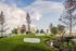 Urban rooftop oasis with lush green grassy mounds, surrounded by trees and city skyline views.