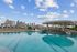Luxurious rooftop pool with stunning city skyline views, featuring modern poolside seating and an open-air pavilion.