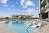 Luxurious rooftop pool with modern lounge chairs, surrounded by lush greenery and panoramic city views.