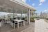 Chic rooftop patio featuring elegant seating, lush greenery, and stunning cityscape views, ideal for outdoor dining and relaxation.