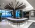 Elegant and modern lounge featuring a stylish bar counter with sleek barstools, artistic lighting design, and panoramic city views.