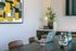 Modern conference room with sleek laptop, vibrant abstract art, elegant decor, and refreshing drinks on a stylish wooden table.