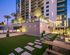 Luxurious urban apartment building with modern exterior, lush landscaping, and inviting outdoor seating areas at twilight.