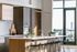 Sleek and modern kitchen with an elegant island, stylish pendant lighting, and breathtaking views through large windows.