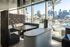 Luxurious lounge area with modern decor and panoramic cityscape view by a sunlit poolside.