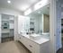 Modern bathroom with dual vanity sinks, large mirror, and spacious walk-in closet, offering elegance and functionality.