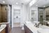 Luxurious bathroom featuring elegant glass shower, sleek double sink vanity, and expansive walk-in closet.