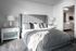 Elegant bedroom with a plush gray bed and sleek decor leading to a luxurious en-suite bathroom.