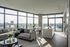 Bright, modern living space with floor-to-ceiling windows, elegant furnishings, and a stunning city view.