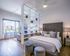 Luxurious studio bedroom with stylish shelving, modern decor, and a stunning city view through expansive windows.