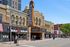 Vibrant city street with a historic theater marquee, boutique shops, and colorful art in a lively urban setting.