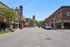 Charming urban street view with classic theater marquee, vibrant storefronts, and a distant historic tower under a clear blue sky.