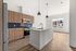Modern kitchen with sleek island, elegant wooden cabinets, stainless steel appliances, and large windows offering natural light.