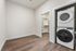 Bright utility room with modern stacked washer and dryer, featuring a spacious walk-in closet and elegant hardwood flooring.