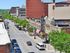 Vibrant urban street view featuring a historic theater marquee, lush green trees, and bustling pedestrian activity.