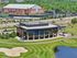 Elegant clubhouse with modern glass facade overlooking lush green golf course and serene pond, ideal for leisure and social events.