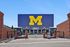 Vibrant stadium entrance showcasing a large 'M' sign and championship banners, inviting an exciting sports atmosphere.