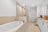 Luxurious bathroom with a sleek soaking tub, modern glass-enclosed shower, and elegant vanity area.