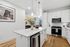 Modern kitchen with sleek white cabinets, elegant island, and cozy living area view, perfect for city living.
