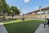 Inviting pet-friendly park with green space, seating, and playful tunnel under sunny skies.