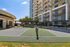 Luxurious high-rise apartments with modern balconies overlooking a pristine tennis court, surrounded by lush greenery.