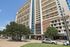 Modern high-rise apartment building with spacious balconies, lush greenery, and a welcoming entrance, perfect for comfortable urban living.