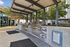 Modern outdoor grilling area featuring sleek stainless steel barbecues with stylish tile surroundings, set against a backdrop of lush greenery.