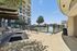 Modern outdoor recreational area with BBQ grills, benches, and a fenced sports court, adjacent to a stylish multi-story apartment building.