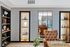 Chic living space with elegant tan armchair, modern shelving, artful decor, and a stylish mirror accentuating an inviting ambiance.