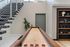 Chic modern interior featuring a sleek, open staircase, a shuffleboard table, and elegant shelving with decorative accents.