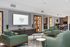 Elegant living area featuring modern green sofas, a sleek entertainment center, and tastefully decorated shelves. Spacious open-concept with a cozy dining nook, perfect for entertaining.