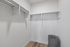 Spacious walk-in closet with elegant shelving and sleek wood flooring, perfect for organized storage.