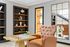 Elegant reading nook featuring a plush leather armchair, a wooden chessboard, and modern built-in shelving with decorative accents.