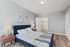 Chic bedroom with a plush navy bed, elegant side tables, and stylish wall art, featuring a spacious walk-in closet.