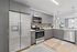 Modern kitchen with sleek stainless steel appliances, gray cabinetry, and a spacious open layout accented by stylish pendant lighting.