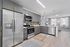 Modern kitchen with sleek gray cabinets, stainless steel appliances, and open layout leading to a bright living area with large windows and stylish decor.