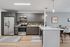Modern kitchen with sleek gray cabinets, stainless steel appliances, and stylish lighting, leading to an elegant dining area.