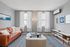 Bright and inviting living room with elegant decor, featuring a warm leather sofa, chic glass coffee table, and modern art on the walls.