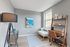 Bright and stylish home office with modern decor, featuring a wooden desk, cozy seating, and large window with natural light.