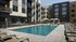 Modern apartment complex with a stunning outdoor pool, elegant poolside loungers, and cozy cabanas, surrounded by lush landscaping.