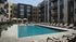 Modern apartment complex with a luxurious outdoor pool, surrounded by stylish sun loungers and elegant cabanas, offering a perfect retreat for relaxation.