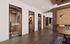 Modern office interior with glass-walled private rooms and stylish decor, featuring vibrant artwork and sleek wooden accents.