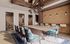 Luxurious dining area featuring a modern wooden table, vibrant upholstered chairs, and elegant pendant lighting against a stylish brick wall backdrop.