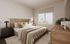 Bright and elegant bedroom featuring a cozy modern bed, soft lighting, and a large window with scenic views.