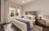 Elegant bedroom with large window views, featuring a plush bed, modern accents, and natural light.