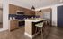 Modern kitchen with sleek wooden cabinetry, stainless steel appliances, blue tile backsplash, and a stylish island with seating.
