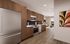 Modern kitchen with sleek wooden cabinetry, stainless steel appliances, and cozy living area offering a warm, inviting atmosphere.