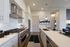 Modern kitchen with sleek white cabinetry, stainless steel appliances, and elegant pendant lighting over a spacious island.